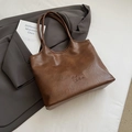 Borsa tote vintage in pelle PU marrone scuro con logo su sfondo di abito grigio - Marrone Senza Ciondolo