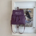 Detail view of purple canvas backpack showing white embroidery and drawstring closure - Purple