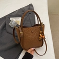 Detail of a brown leather bucket bag with leopard embossed patterns and wooden bead tassel - Brown Leopard (With Pendant)