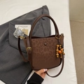 Close-up of brown faux suede bucket bag featuring leopard pattern and wooden bead charm - Leopard Coffee With Charm
