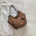 Borsa tote leopardata con cinturini in pelle marrone e ciondolo su sfondo bianco - Marrone