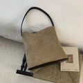Dettaglio borsa a secchiello retrò in pelle scamosciata con spallacci neri su sedia - Cachi