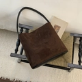 Dettaglio della borsa a tracolla in pelle scamosciata marrone su sedia di design - Marrone