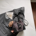 Detalle del bolso de cubo con estampado de leopardo, cuero negro y colgante de oso - Negro Con Colgante