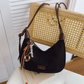 Dettaglio borsa hobo in pelle scamosciata nera con nappina appesa a una sedia intrecciata - Con Ciondolo / Nero