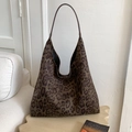 Detalle de bolso hobo con estampado de leopardo sobre un taburete de madera en un salón - Verde