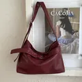 Vista dettagliata della borsa a tracolla in pelle PU rosso scuro con fibbia su una parete - Rosso