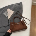 Detalle de bolso tote de ante marrón oscuro con cierre giratorio plateado y asas dobles - Café sin colgante