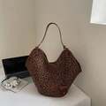 Detail der Leopard-Print-Tasche mit braunem Lederbesatz neben einem Laptop - Leopardenmuster