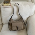 Retro brown suede hobo bag with buckled pocket shown on a soft white sofa background - Khaki
