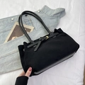 Minimalist black suede tote bag with golden buckle detail on casual denim background - Black