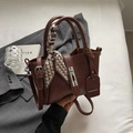 Detail of dark brown leather bucket bag with silver turn-lock and silk scarf handle - Brown