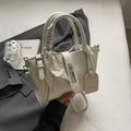 Close-up of cream textured bucket bag with silver twist lock and decorative silk scarf handle - Silver
