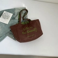 Detail of suede tote bag with green embroidery and plaid straps on a white background - Brown