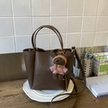 Détail du sac à main en cuir marron foncé avec un petit ours en peluche attaché - Cacao Avec Charme
