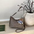 Detail of a brown suede hobo bag with a cute bear charm in a lifestyle interior setting - Gray With Pendant