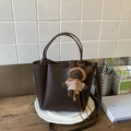 Vue détaillée du sac cabas en cuir grainé marron avec un pendentif ours sur un plateau - Café Avec Pendentif