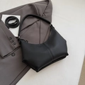 Minimalist black pebble leather hobo bag with dual straps on a grey blazer - Black