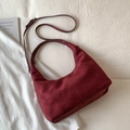 Detail der burgunderroten Wildleder-Hobo-Tasche mit feinen Nähten auf weißem Stoffhintergrund - Groß / Burgunderrot