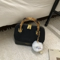Detail van zwarte schelptas met bamboe handvat en wit pluche monster accessoire - Zwart Met Hanger