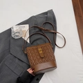 Borsa a secchiello trapuntata marrone con chiusura dorata su un blazer grigio - Marrone senza ciondoli
