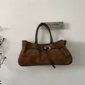 Detailansicht der braunen Tragetasche aus Rauleder mit Lederriemen und Silberschnalle - Braun