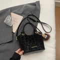 Dettaglio borsa a secchiello nera floccata animalier con logo dorato e ciondolo di peluche - Nero (Con Ciondolo)