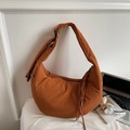 Detail of caramel crescent crossbody bag featuring waffle texture fabric and drawstring - Brown