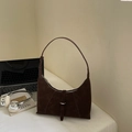 Sac hobo en daim marron foncé avec bandoulière réglable sur un bureau blanc minimaliste - café