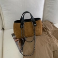 Dettaglio della borsa in pelle scamosciata marrone con catena d'argento su divano bianco - Marrone