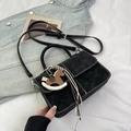 Detail of black crossbody bag with white stitching, horse charm, and woven tassels - Black (With Horse Charm)