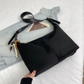 Detailed close-up of a black suede handbag featuring a stylish beaded charm accessory - Black