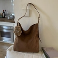 Detailaufnahme der braunen Wildledertasche mit Teddybär-Anhänger auf einem Sofa - Braun (Mit Anhänger)