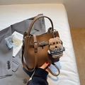 Détail d'un sac seau en cuir grainé marron avec fermoir métallique et breloque petit ours - Marron avec pendentif