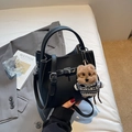 Sac à main en cuir noir avec charmant petit chiot en peluche sur fond de studio épuré - Noir avec pendentif
