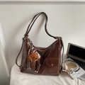 Gros plan du sac hobo en similicuir marron brillant avec un porte-clé ours en peluche - Marron (Avec Pendentif)