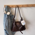 Donkerbruine retro draagtas met witte pluche beer hanger aan een houten haakje aan de muur - Koffie Met Bedels