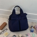 Detailansicht der dunkelblauen Multi-Pocket-Nylontasche mit Lifestyle-Zubehör auf Teppich - Dunkelblau