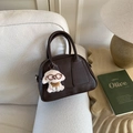 Detail der dunkelbraunen Bowlingtasche aus Kunstleder mit Welpenanhänger auf Sofa - Kaffee Mit Anhänger