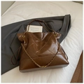 Detailed macro view of brown quilted tote bag with golden metal chain strap and stitching - Brown