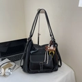 Schwarze Schultertasche aus Kunstleder mit weißen Nähten und flauschigem Bärenanhänger - Mit Anhänger / Schwarz