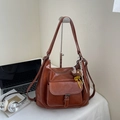 Braune Retro-Ledertasche mit niedlichem Bärenanhänger auf einem weißen Schreibtisch - Mit Anhänger / Gelbbraun