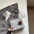 Close-up of leopard print handbag featuring a plush charm and gold logo lettering - With Pendant / Silver