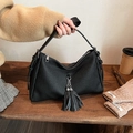 Makro-Detail der schwarzen plissierten Kunstledertasche mit Metallketten-Fransenanhänger - Schwarz