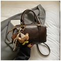 Detail of vintage brown Boston bag featuring embossed logo and cute plush bear charm - Coffee With Pendant