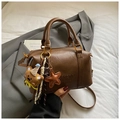 Detail view of brown Boston bag with embossed logo and cute knit bear charm accessory - Brown with Pendant