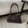 Detail van vintage bruine schoudertas met gouden gesp op een wit pluche tapijt - Bruin