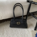 Detail van zwarte retro baguette tas met gouden gesp en glanzende leerachtige textuur - Zwart