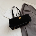 Close-up of black suede baguette bag with golden metal twist lock and protective feet - Black