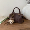 Detalle del bolso Boston marrón mate con un colgante de perro de peluche suave - Café Con Colgante
